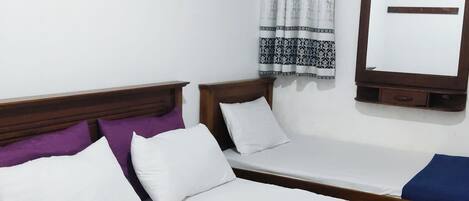 A room with two beds, a wooden headboard, a wall-mounted mirror, and a decorative wooden piece.