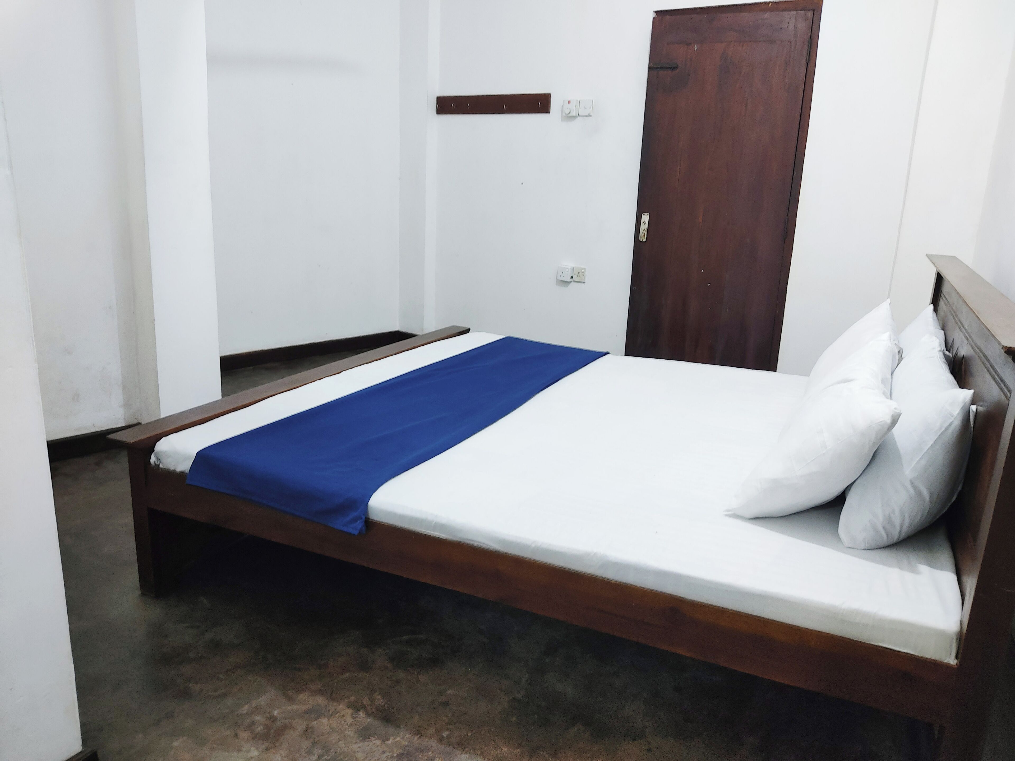A single bed with a wooden frame and a blue bedspread.