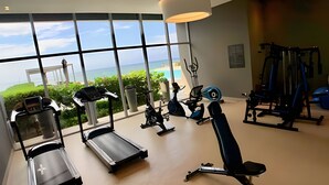 A gym with treadmills, stationary bikes, and weight machines, with a view of the ocean through large windows. - 2704 Morros City - Spectacular beachfront apt (Cartagena de Indias)