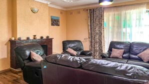 Un salon doté d’une cheminée, de canapés en cuir et d’un plafond orné de moulures décoratives.