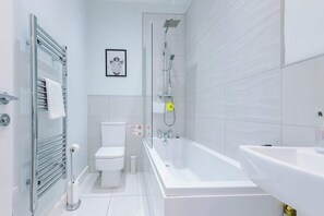 A modern bathroom with a glass shower enclosure, a white toilet, and a bathtub.