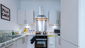 A modern kitchen with white cabinets, a stainless steel range hood, an oven, and a microwave.