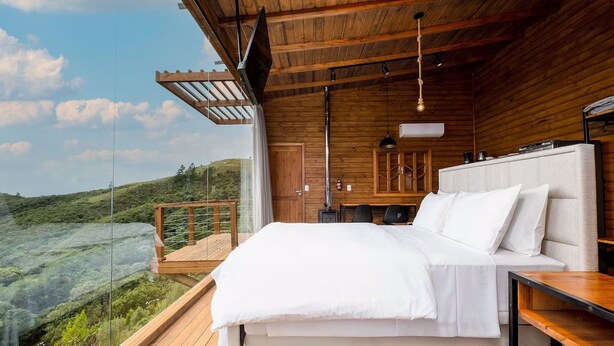 Ein Schlafzimmer mit einem großen Bett, Holzboden und Blick auf eine grüne Landschaft.