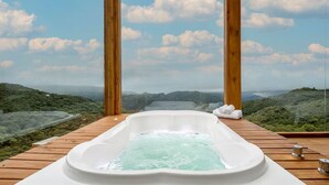 Ein Whirlpool auf einer Holzterrasse mit Blick auf eine malerische Berglandschaft.