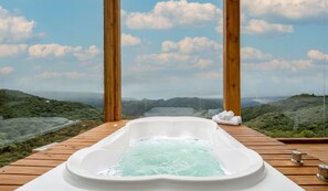 A hot tub on a wooden deck with a scenic mountain view.