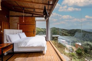 Un dormitorio con una cama grande, paredes de madera y vistas a un paisaje montañoso.