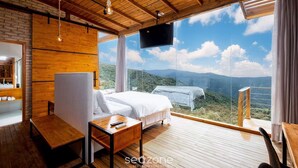 Ein Schlafzimmer mit großem Fenster, Holzboden und einem Bett mit weißen Bettwäsche.