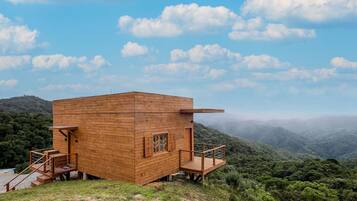 Una cabaña de madera con balcón, rodeada de un paisaje montañoso.
