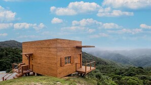 Eine Holzhütte mit Balkon, eingebettet in eine gebirgige Landschaft.