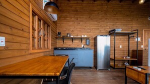 Eine Holzhütten-Küche mit Esstisch, Stühlen, einem Kühlschrank und einer Kaffeemaschine.