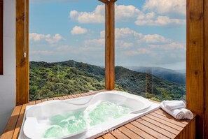 A wooden deck with a hot tub and towels, overlooking a lush forested landscape. - Linda cabana com jacuzzi VST013 (Anitapolis)