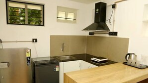 A compact kitchen with a refrigerator, a sink, a stove, and a wooden countertop.