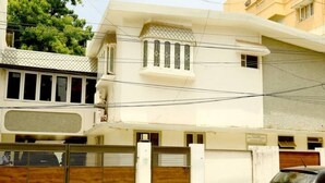 A white building with a gated entrance, a parked car, and a balcony with a patterned railing.