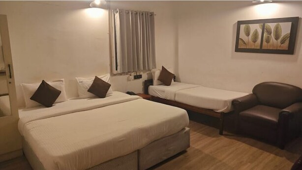 A hotel room with two beds, a chair, and a painting on the wall.