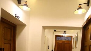 A hallway with wooden flooring, two doors labeled "G-02", and wall-mounted lighting fixtures.