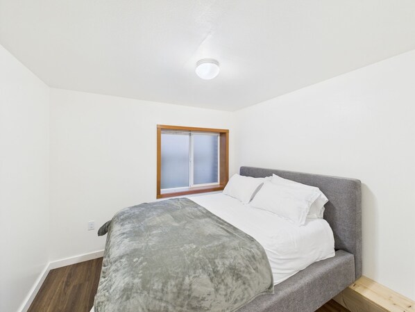 A bedroom with a bed, a window, and a ceiling light.
