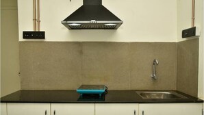 Una cocina con encimera negra, un lavamanos de acero inoxidable y un electrodoméstico azul sobre la encimera.