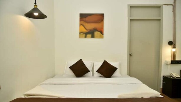 Una habitación de hotel con una cama, un cuadro en la pared y una puerta.