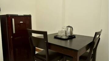 A dining table with chairs, a refrigerator, and a tray with glasses and a kettle.