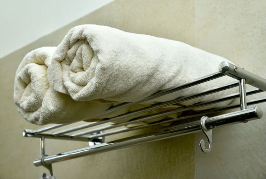 Une serviette blanche, soigneusement pliée, est posée sur un porte-serviettes chromé dans une salle de bain.