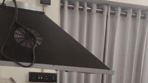 Una cocina con estufa negra, pileta de acero inoxidable y extractor de aire negro.