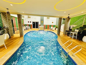 An indoor swimming pool with a central water feature, surrounded by seating areas and a staircase. - Presken Awolowo Way - Ikeja (Lagos)