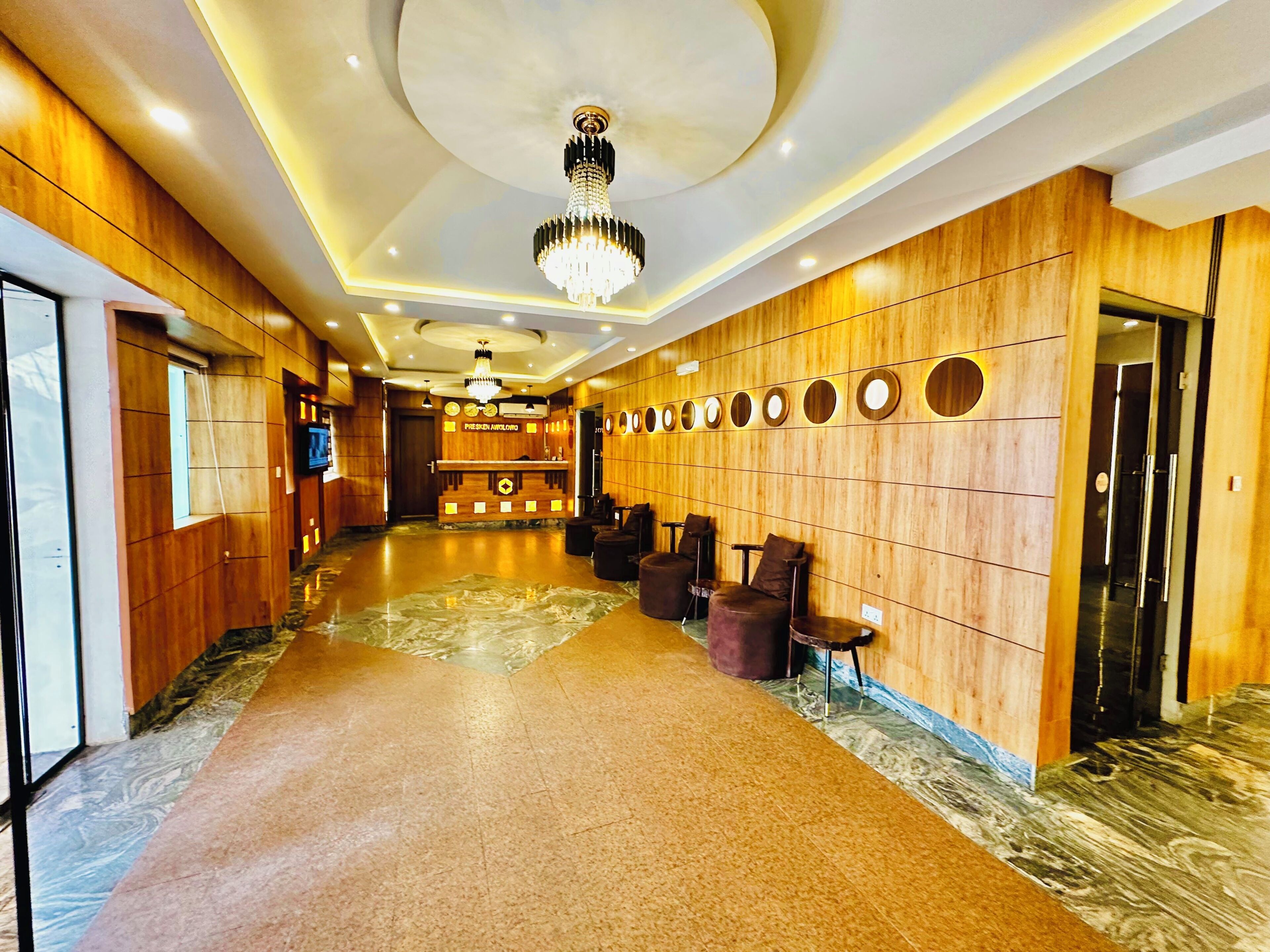 A hotel lobby with a reception desk, seating area, and a chandelier.