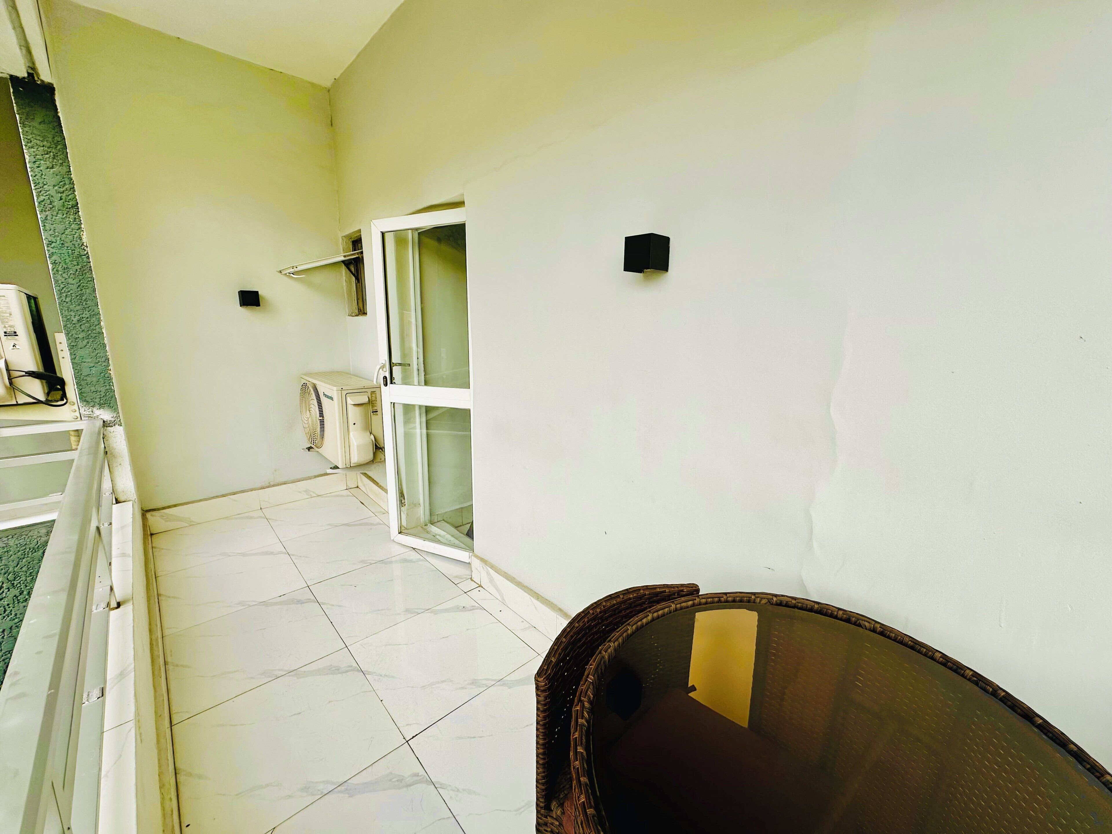 A corridor with a tiled floor, a door with a glass panel, and a wall-mounted air conditioning unit.