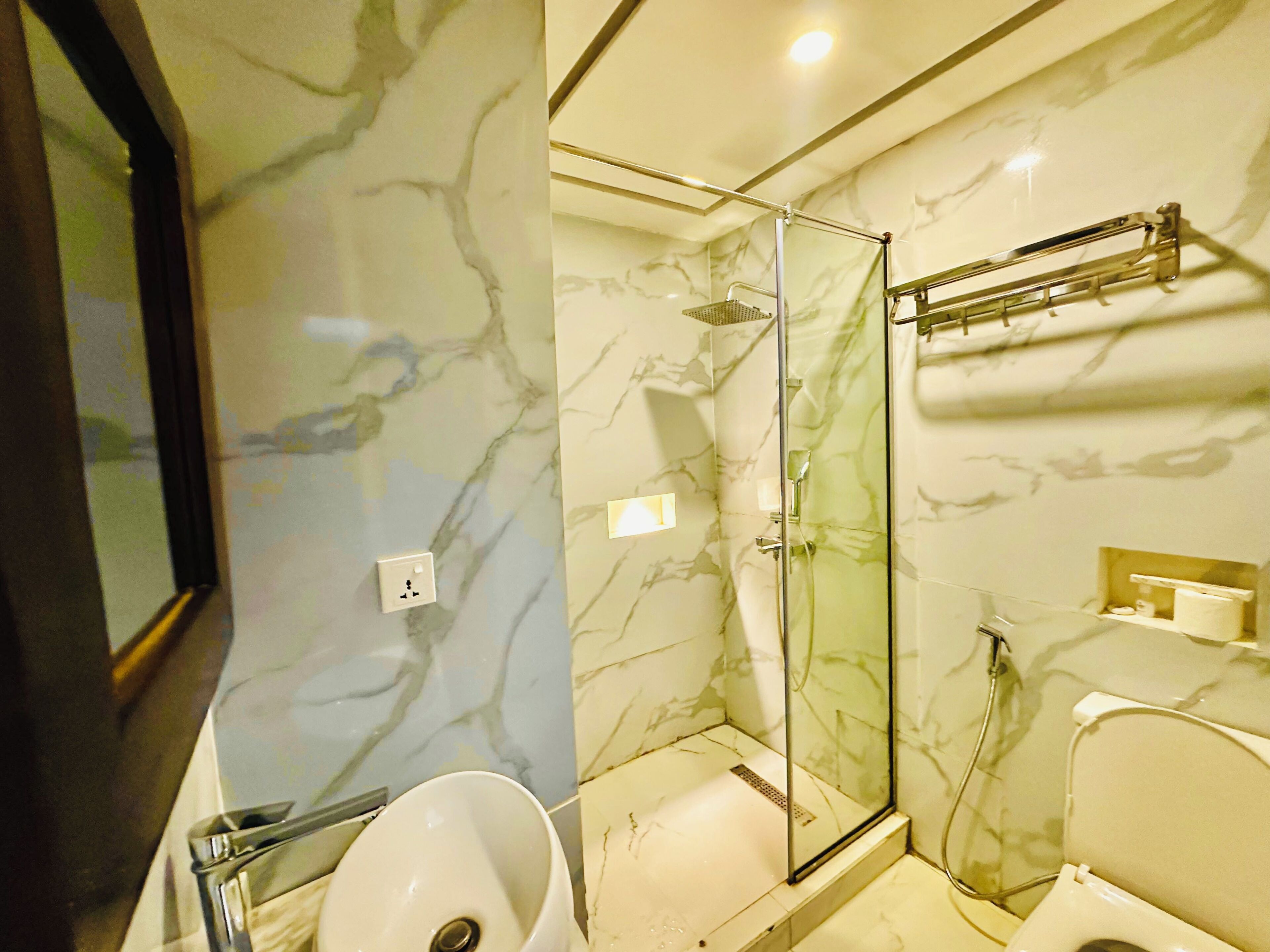 Un baño con ducha de vidrio, lavamanos e inodoro.