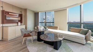 A modern living room with a sofa, two coffee tables, a chair, and a built-in kitchen unit. - Holiday Inn Changchun High Tech Zone by IHG (Changchun)