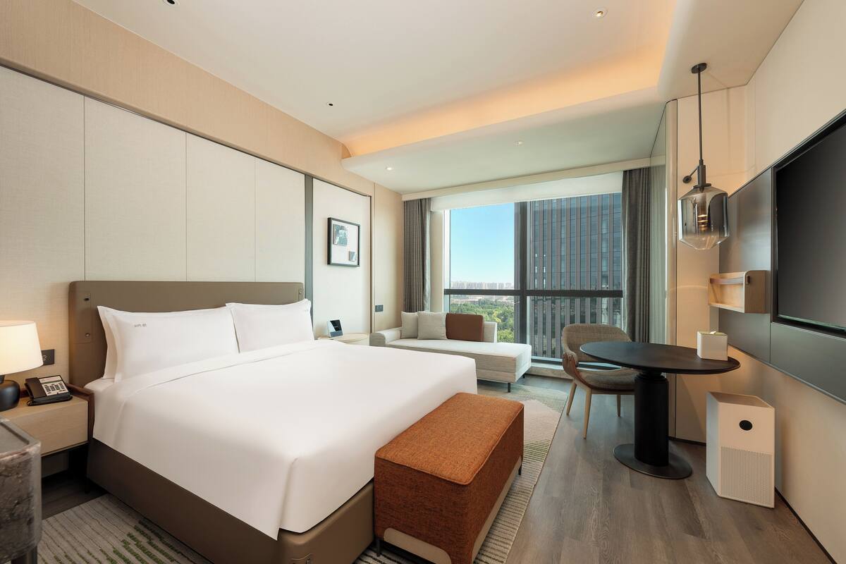 Une chambre d’hôtel moderne équipée d’un grand lit, d’un canapé, d’une table à manger et d’un téléviseur.