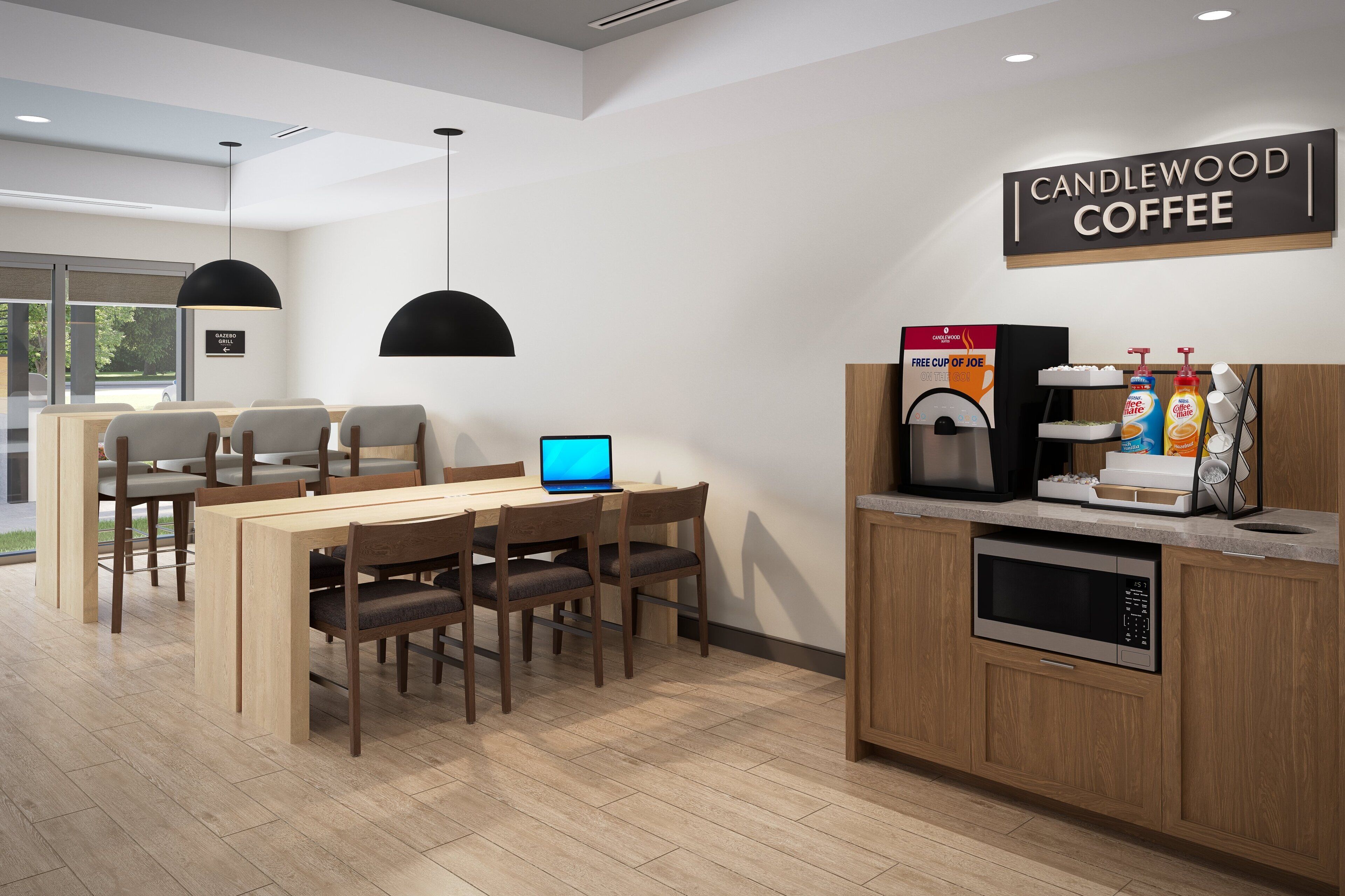 Un moderno caffè con un bancone in legno, un laptop e una macchina per il caffè.