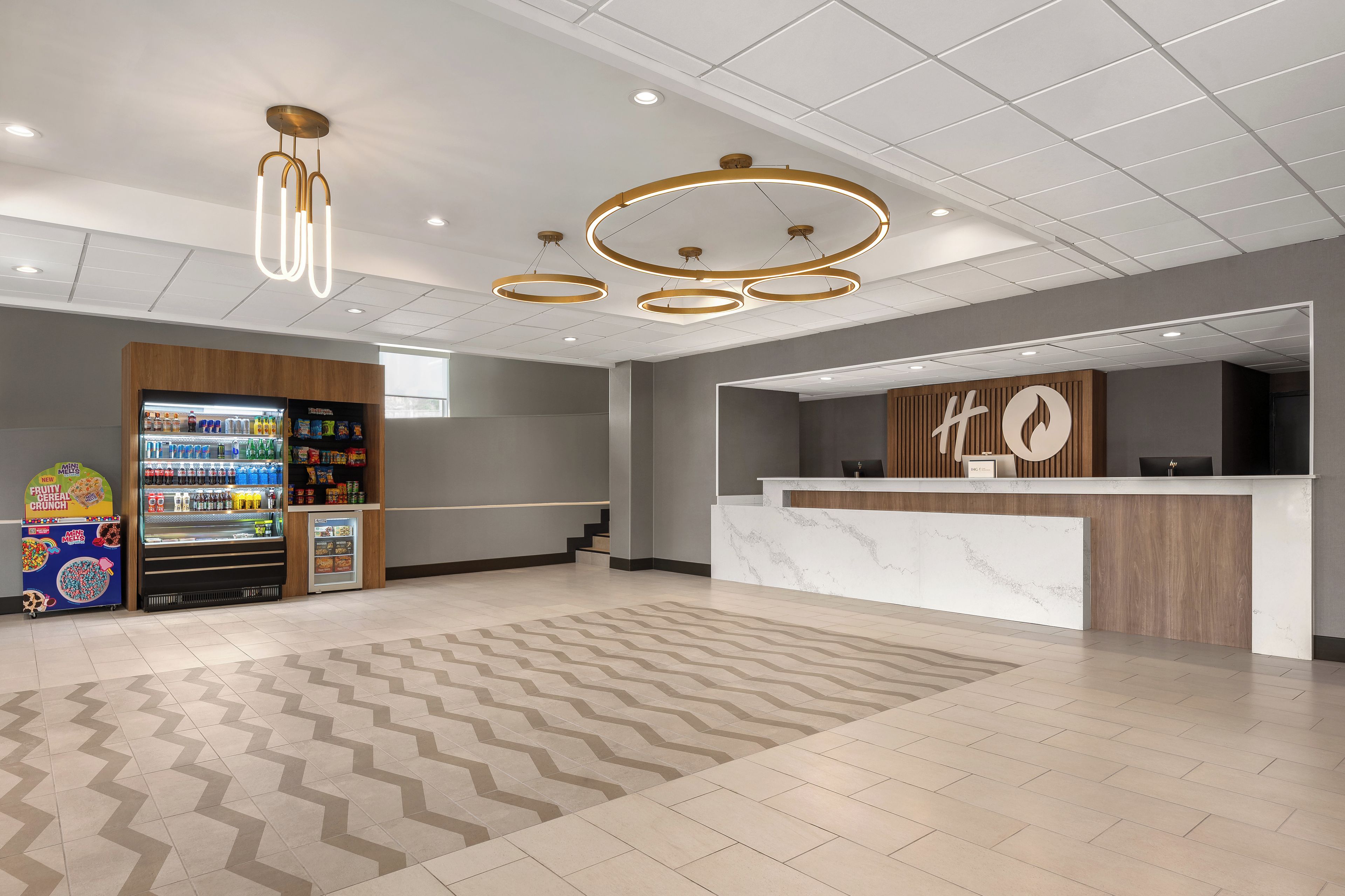 Et hotellobby med en receptionsdisk, automater og et mønstret tæppe.