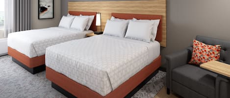 A hotel room with two beds, a sofa, a nightstand, and a lamp.