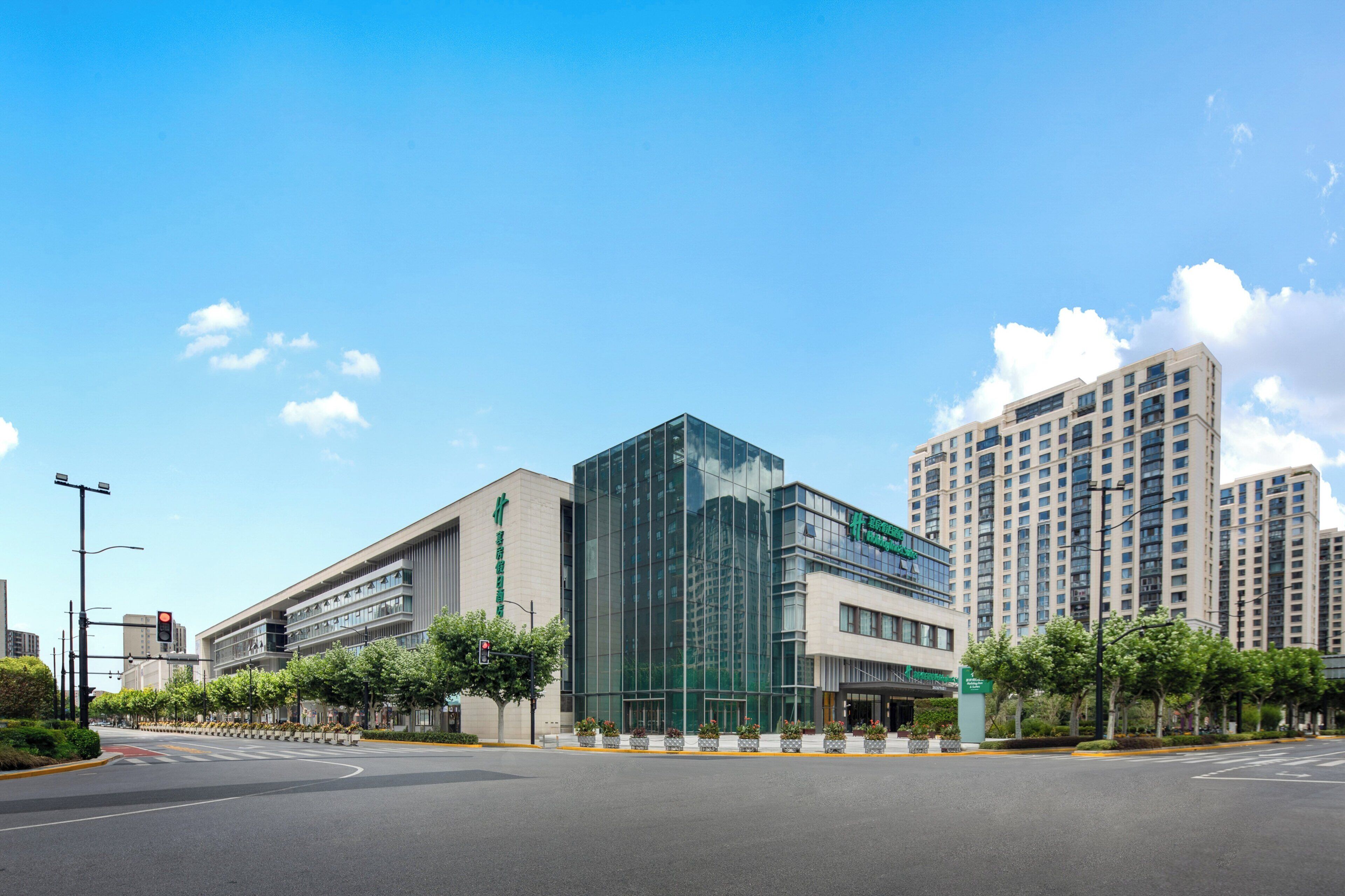 A modern building with a glass facade, a large entrance, and a parking lot.