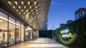A modern hotel entrance with a glass facade, a geometric ceiling design, and a well-lit pathway leading to the building. - Holiday Inn Hotel & Suites Shanghai Changfeng by IHG (Shanghai)