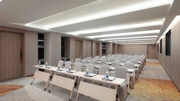 A conference room with rows of tables, chairs, and a carpeted floor.
