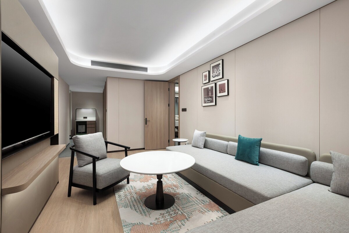A modern living room with a sofa, armchair, and round table.