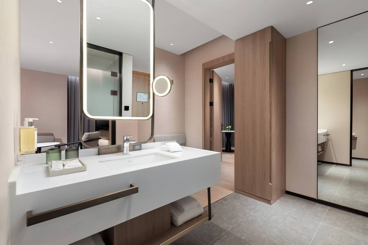 A modern bathroom with a large mirror, two sinks, and a towel rack.