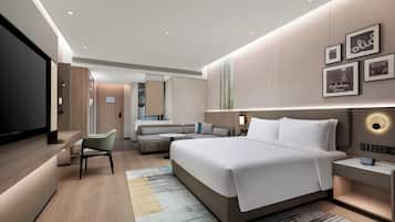 A modern hotel room with a large bed, a sofa, a desk, and a TV.