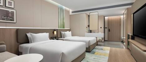 A hotel room with two beds, a small table, a TV, and a bathroom with a mirror and sink.