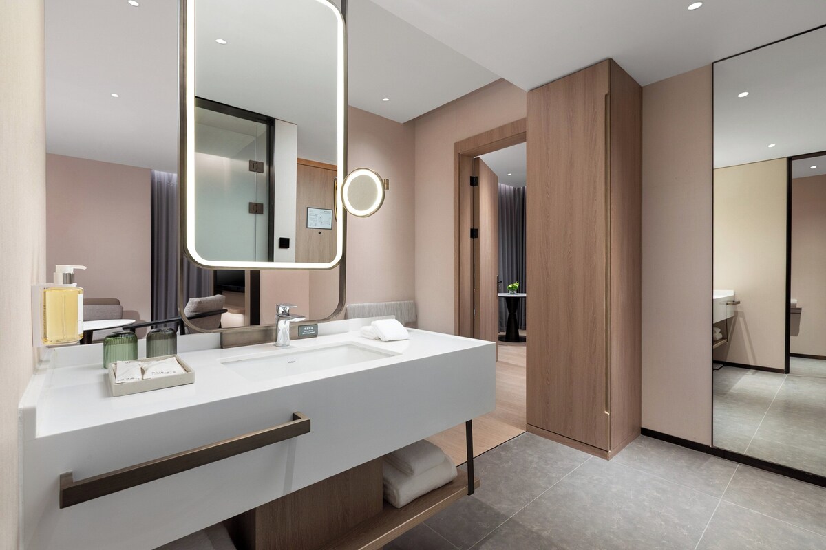 A modern bathroom with a large mirror, two sinks, and a towel rack.