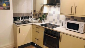 A modern kitchen with a sink, stove, microwave, and cabinets.