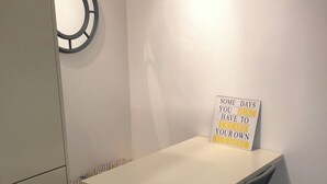 A small, neatly arranged room with a white table and two chairs, a wall clock, and a motivational sign.