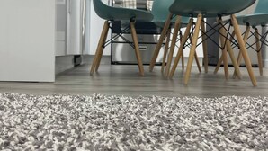 A modern kitchen with white cabinets, a microwave, and a dining area with teal chairs and a grey shag carpet. - Comfy 2BR Basement Getaway (Edmonton)