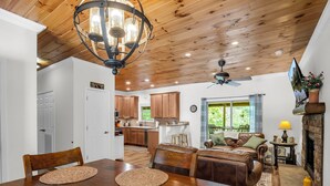 A spacious living area with a wooden dining table, leather sofa, and a fireplace.