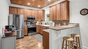 A modern kitchen with wooden cabinets, stainless steel appliances, and a central island with stools.