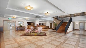 A spacious lobby with a central seating area, a staircase, and a reception desk. - Central City Winter Escape HotTub HeatedPool Sauna (Auckland)