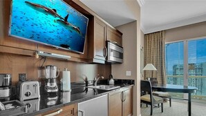Una cocina moderna con un televisor grande, electrodomésticos integrados y un comedor con vistas a la ciudad.