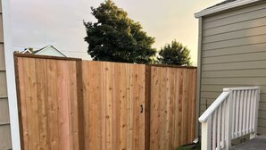 A wooden fence with a gate, a grassy area, and a staircase leading to a building. - Welcoming 2-bedroom house 10min walk to the beach in Seaside (Seaside)